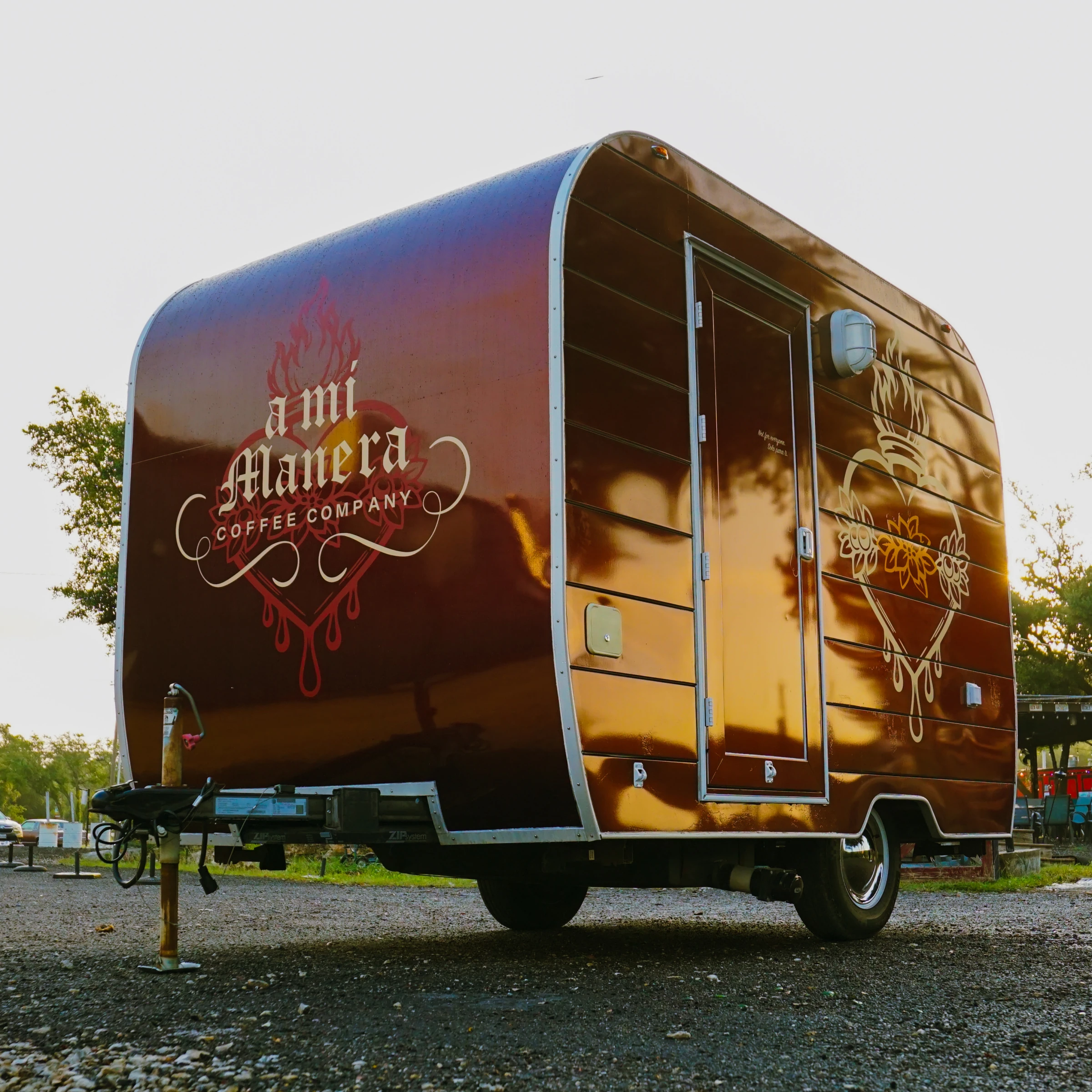 Side angle of the A Mi Manera coffee trailer — candy maroon with gold-leaf lettering